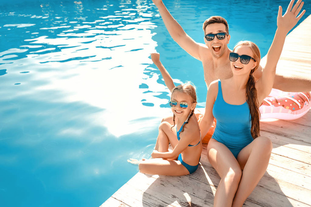 Gelukkige familie zittend in de buurt van het zwembad - Foto, afbeelding