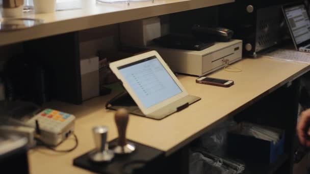 Een close-up van een mannelijke kassier met een touchpad achter een teller in een koffieshop - Video
