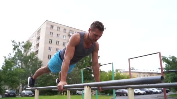 Jovem está fazendo flexões em barras paralelas ao ar livre
 - Filmagem, Vídeo