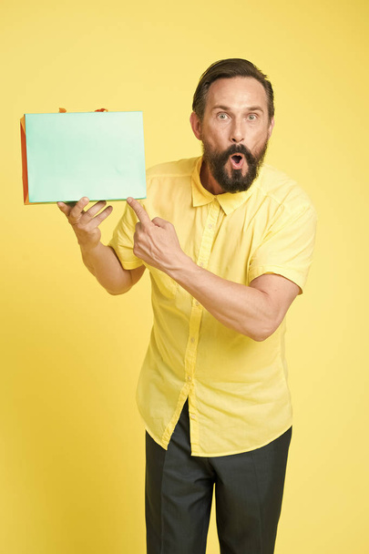Online shopping. Profitable purchase. Shop assistant or sales expert. Shopping happiness. Man emotional enjoying shopping. Bearded mature man with shopping bag on yellow background. Sale and discount - Photo, image
