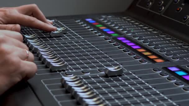Az ember egy professzionális elektronikus audio mixeren dolgozik. Hangcsatornák hangolására szolgáló vezérlőpanel - Felvétel, videó