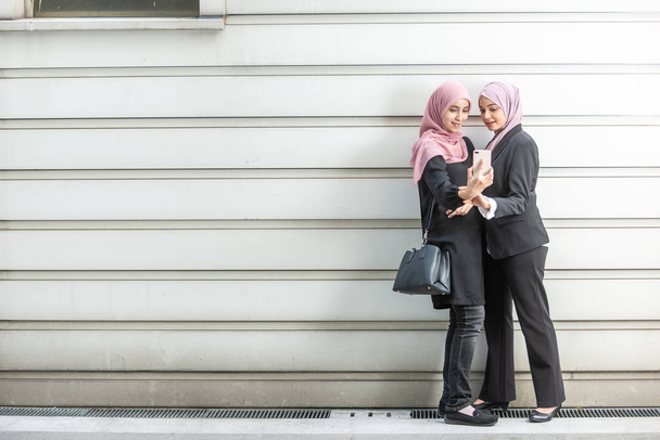 Азіатські дівчата мусульманські беручи селфі. Зовнішня настройка. - Фото, зображення