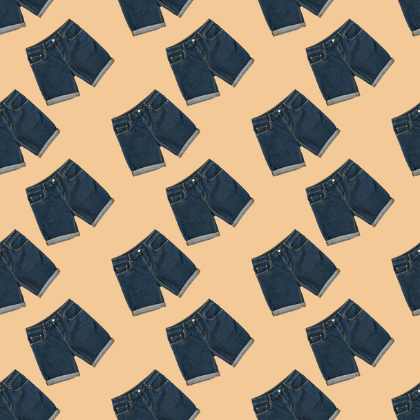 Bezproblémové schéma modrých džíšových kraťat na béžovém pozadí. Módní unisexuální oblečení. - Fotografie, Obrázek
