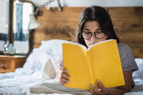 woman laying in bed and reading book - Photo, Image