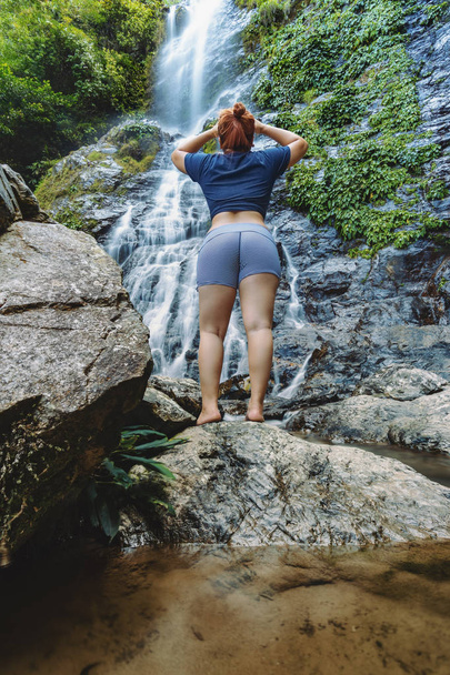 Woman standing and looking up at the Langganan Waterfall, Poring. - Foto, Imagem
