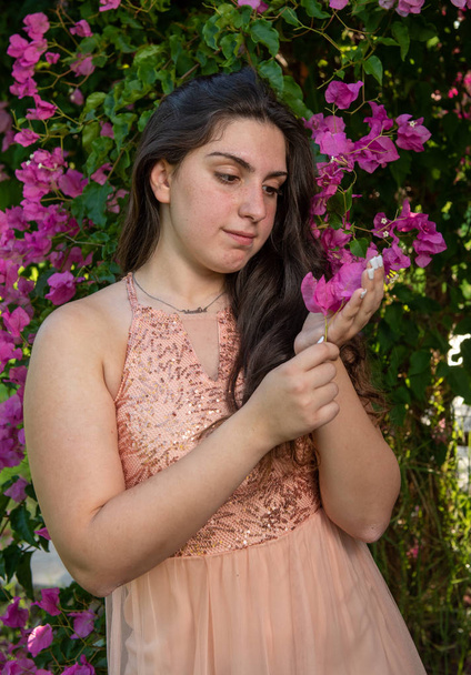 Ελκυστική νεαρή όμορφη κυρία, απολαμβάνοντας τα ροζ ανθοφορία λουλούδια - Φωτογραφία, εικόνα