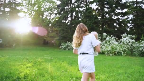 A young mother walks with the baby in the green park. Happy childhood and Parenthood. Love - Záběry, video