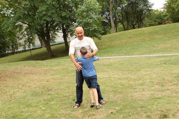 boy, preschooler, primary school student are standing alone with an elderly man, hugging, in the park, concept of family relationships - Fotografie, Obrázek