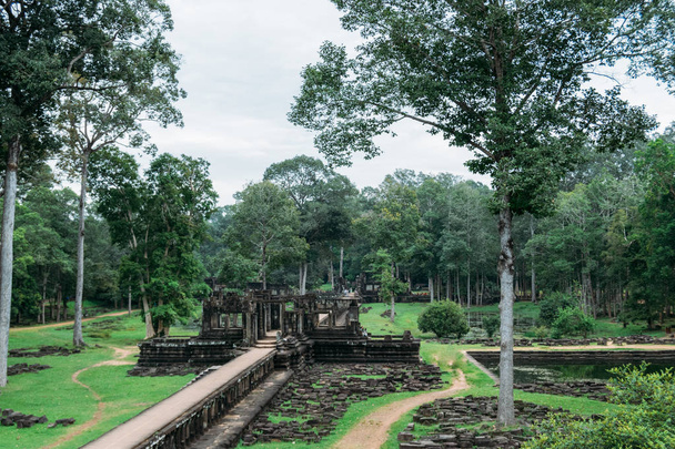 A corridor made in the middle of the garden and many stones thrown on the ground of the ruins of Ankgor Thom in Cambodia - World Heritage by UNESCO in 1992 - Photo, Image