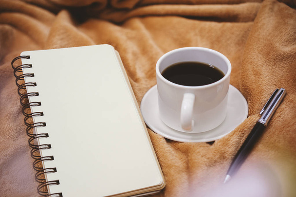 Poznámkový blok, pero a šálek kávy na přikrývce - Fotografie, Obrázek