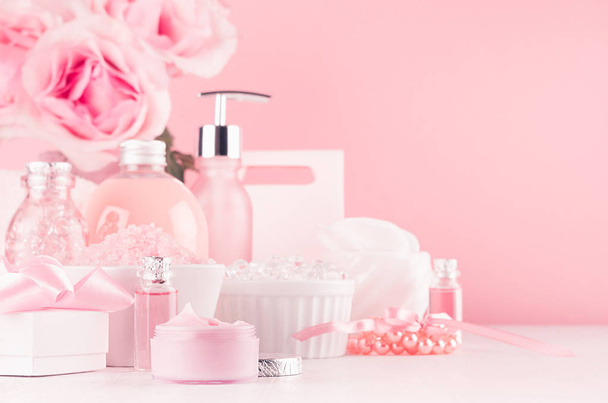 Modern youth bathroom or dressing table design in pastel pink color - fresh pink flowers, cosmetic products, bath accessories, jewelry on white wood board. - Zdjęcie, obraz