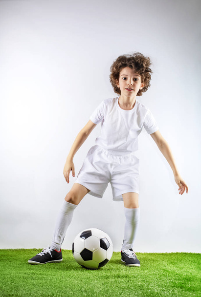 Boy with soccer ball on the green grass. Excited little toddler boy playing football on soccer field against light background. Active childhood and sports passion concept. Save space - Zdjęcie, obraz