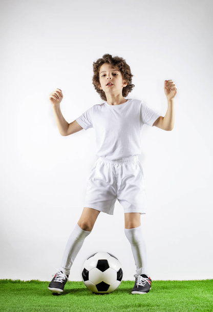 Boy with soccer ball on the green grass. Excited little toddler boy playing football on soccer field against light background. Active childhood and sports passion concept. Save space - Φωτογραφία, εικόνα
