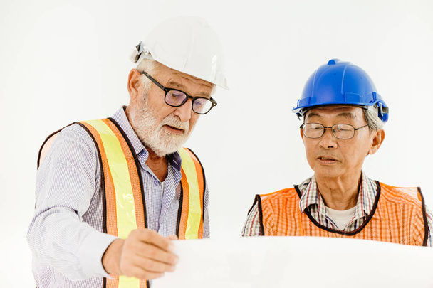 two senior professional architecture engineer consulting with builder foreman for safty and fast building home in construction site looking at blueprint - Photo, Image