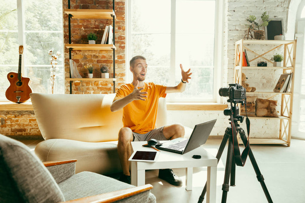 Caucasian male blogger with camera recording video review of gadgets at home - Foto, immagini