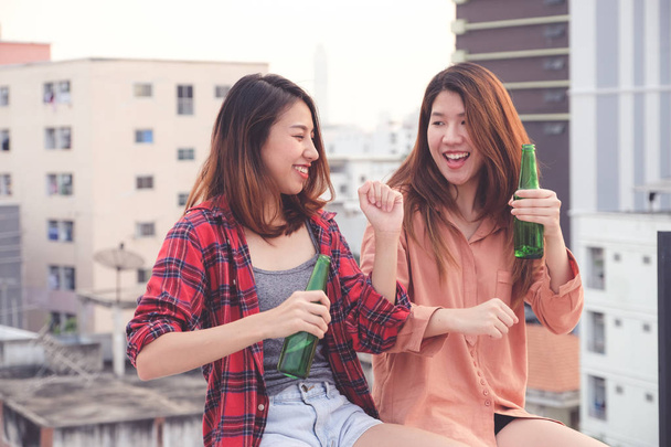 Due donne asiatiche che bevono alla festa sul tetto, celebrazione all'aperto
, - Foto, immagini
