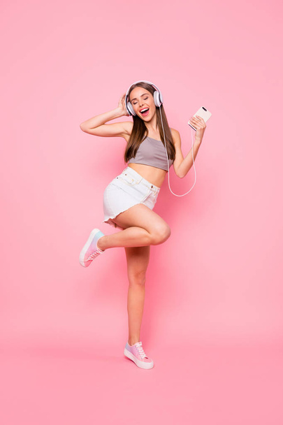 Full length photo of charming youngster having headset closing eyes screaming wearing grey tank-top denim jeans skirt isolated over pink background - Photo, Image