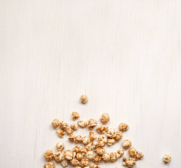 Caramelized popcorn na białym tle drewnianym. Karmelowy popcor - Zdjęcie, obraz