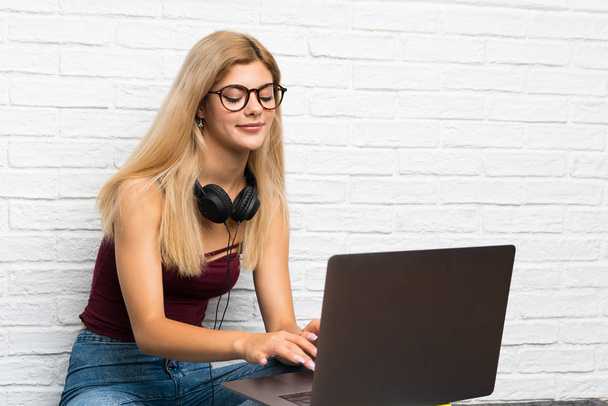 Teenager girl sitting on the floor with her laptop - Foto, Imagen