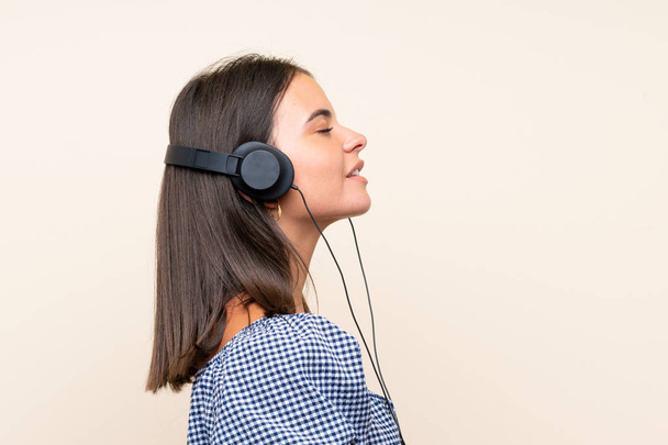 Chica joven sobre fondo aislado escuchando música con auriculares
 - Foto, Imagen