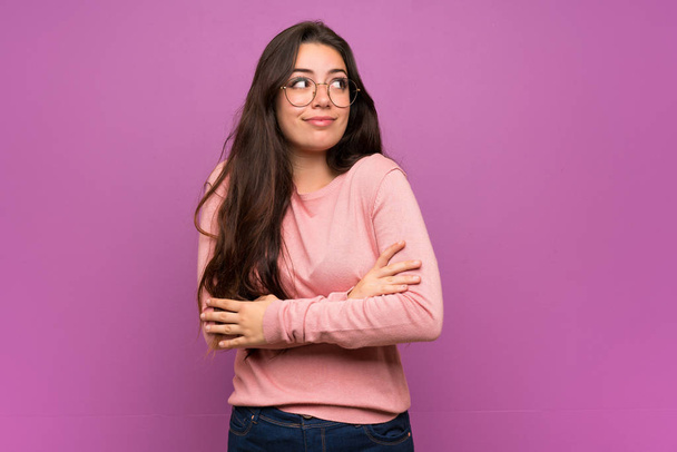 Nastolatka nad fioletową ścianą robi wątpliwy gest podnosząc ramiona - Zdjęcie, obraz