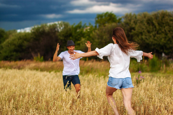 Una joven pareja de pie en el campo y abrazo
.  - Foto, Imagen