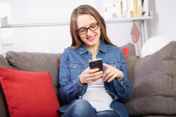 woman talking to mobile on sofa - 写真・画像