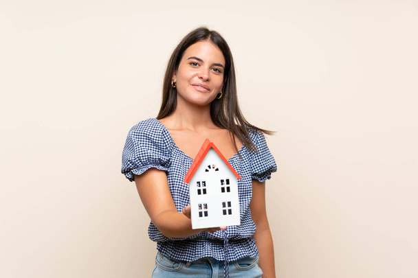 Young girl over isolated background holding a little house - Photo, image