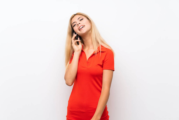 Teenager girl over isolated white background keeping a conversation with the mobile phone - Фото, изображение