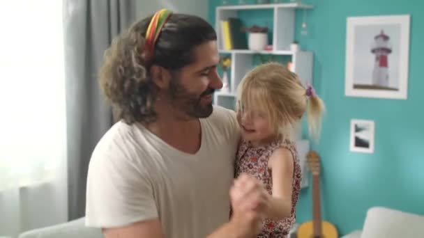 Dad is dancing with his daughter in his arms at home - Felvétel, videó