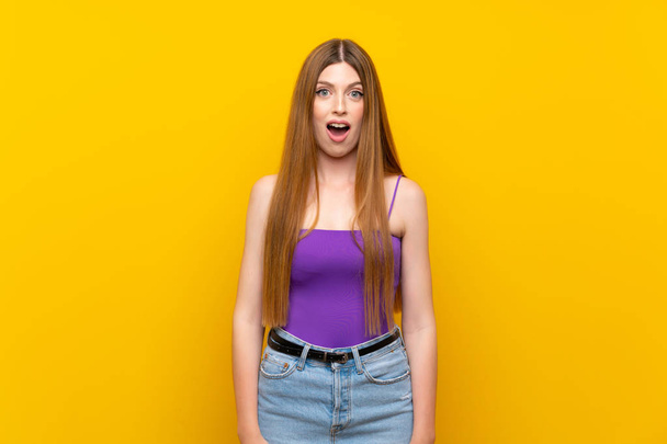 Jonge vrouw over geïsoleerde gele achtergrond met verrassing gezichtsuitdrukking - Foto, afbeelding