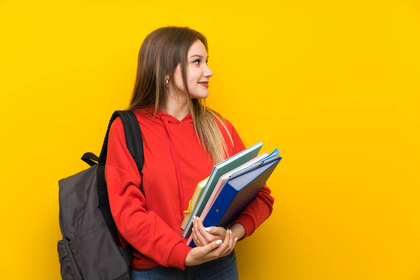 Teenager student girl over yellow background looking to the side - Фото, изображение