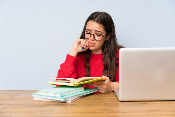 Разочарованная студентка-подросток учится за столом
 - Фото, изображение