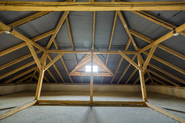 Dachgeschoss eines Gebäudes mit Holzbalken einer Dachkonstruktion und einem  - Foto, Bild