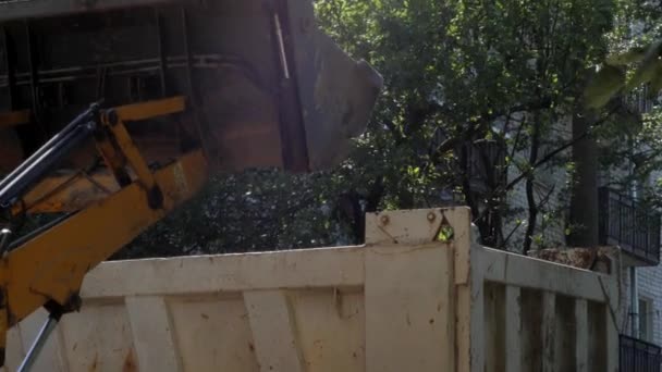 A tractor removes construction debris in the courtyard of a residential building, before laying new asphalt. Sunny summer day. - Footage, Video