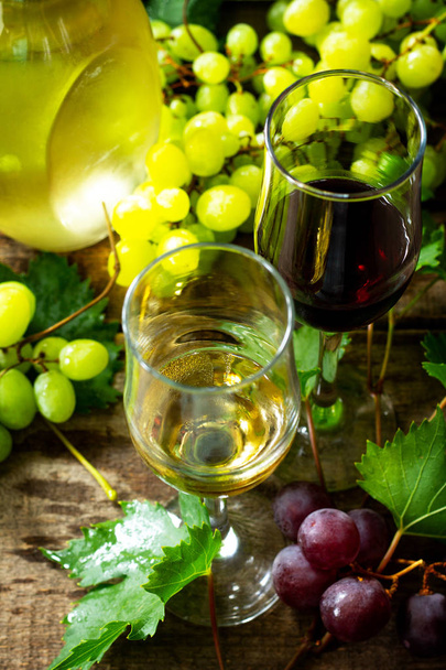 Wine concept. White and Red wine in glasses, bottle, grapes on v - 写真・画像