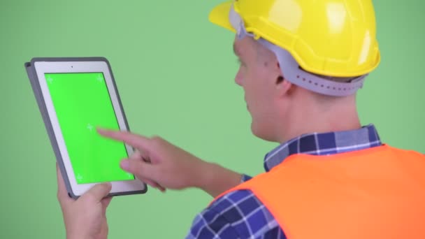 Closeup rear view of young man construction worker using digital tablet - Video, Çekim
