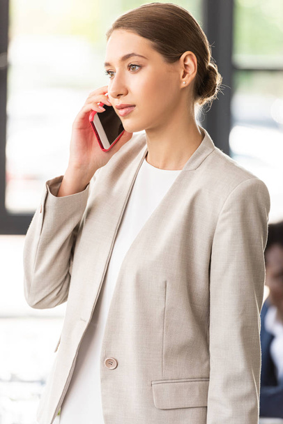 businesswoman in formal wear talking on smartphone in office - Photo, Image