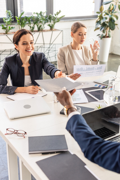частковий погляд на багатонаціональних бізнесменів у формальному носінні за столом під час конференції в офісі
 - Фото, зображення