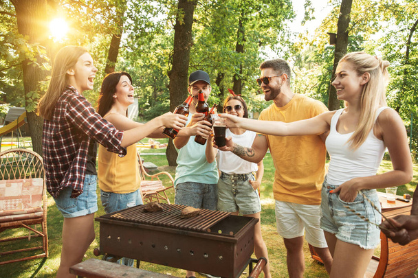 Gelukkige vrienden hebben bier en barbecuefeest op zonnige dag - Foto, afbeelding