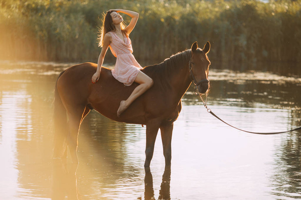 Женщина сидит верхом на лошади у реки
. - Фото, изображение
