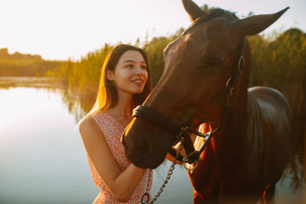 Nainen seisoo hevosen vieressä joen pohjalla
. - Valokuva, kuva