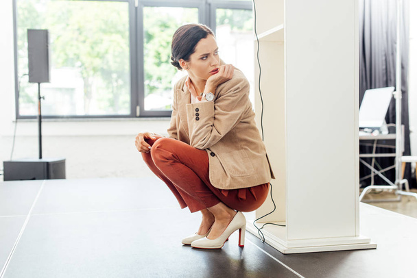 attractive and scared businesswoman in formal wear sitting on floor  - Foto, afbeelding