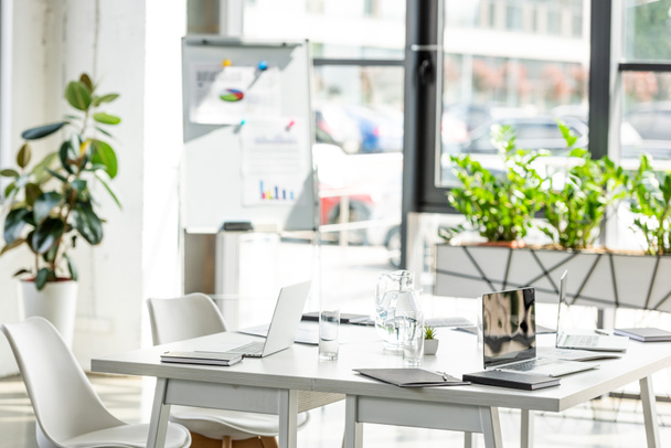 Biuro ze stołem, krzesłami, zielonymi roślinami i urządzeniami cyfrowymi  - Zdjęcie, obraz