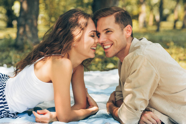 Portrait of happy couple in love dating outdoors at the park on a sunny day. Romantic couple lying on the blanket on the grass during picnic in the nature background. Valentine day. Happy relationship - Φωτογραφία, εικόνα
