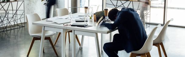 tiro panorâmico de empresário afro-americano dormindo na mesa no escritório
  - Foto, Imagem