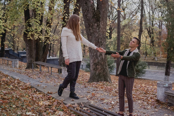 Verliebte Paare stehen auf herbstlichem Laub in einem Park und genießen einen schönen Herbsttag. Mann umarmt Mädchen - Foto, Bild