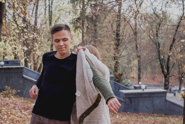 Εφηβικό αγόρι στέκεται στο φθινοπωρινό πάρκο με θηλυκό φιγούρα στο παρασκήνιο. Ωραίος καιρός - Φωτογραφία, εικόνα