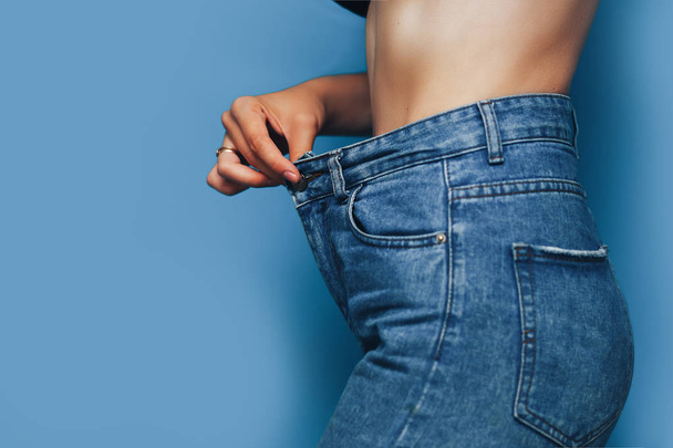 dünner Frauenkörper mit lockerer Hose Jeans, leichter Körper mit lockerer Kleidung, schlanker und gesunder Körper fettarmes Konzept - Foto, Bild