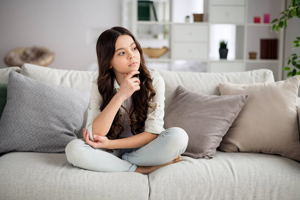 Portrait of her she nice-looking attractive lovely charming cute calm wavy-haired pre-teen girl sitting on divan thinking in light white interior living-room house indoors - Foto, Imagen